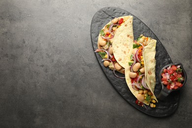 Photo of Tasty vegetarian tacos with beans and quinoa served on grey table, top view. Space for text
