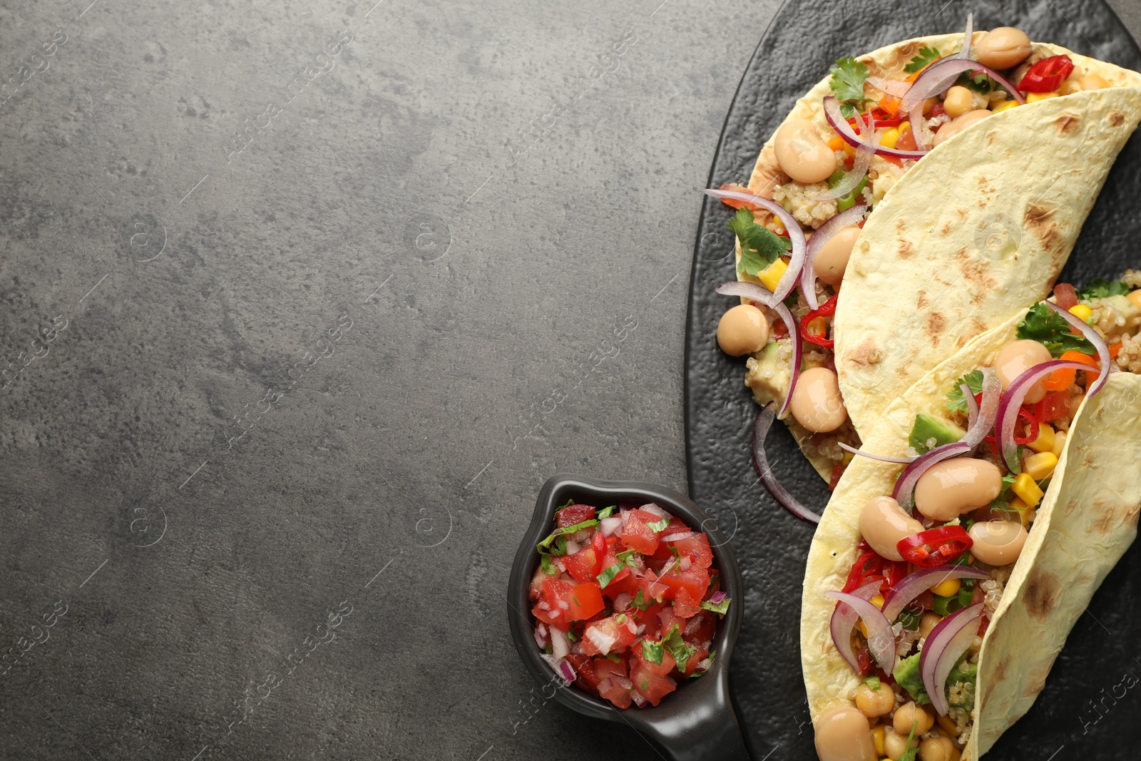 Photo of Tasty vegetarian tacos with beans and quinoa served on grey table, top view. Space for text