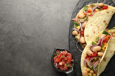 Photo of Tasty vegetarian tacos with beans and quinoa served on grey table, top view. Space for text