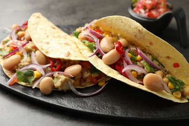 Photo of Tasty vegetarian tacos with beans and quinoa served on grey table, closeup