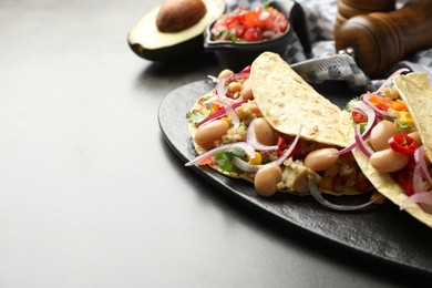 Photo of Tasty vegetarian tacos with beans and quinoa served on grey table, closeup. Space for text