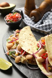 Photo of Tasty vegetarian tacos with beans and quinoa served on grey table, closeup
