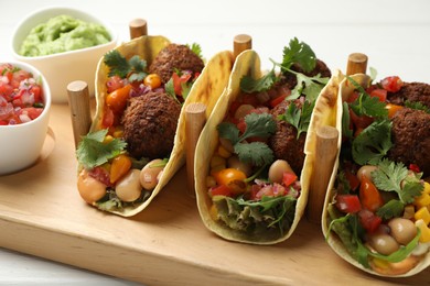 Photo of Tasty vegetarian tacos with falafel served with salsa and guacamole on white wooden table, closeup