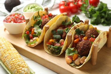 Photo of Tasty vegetarian tacos with falafel served with salsa and guacamole on white wooden table, closeup