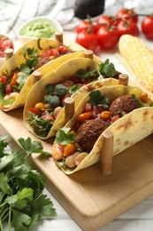 Photo of Tasty vegetarian tacos with falafel served with salsa and guacamole on white wooden table, closeup