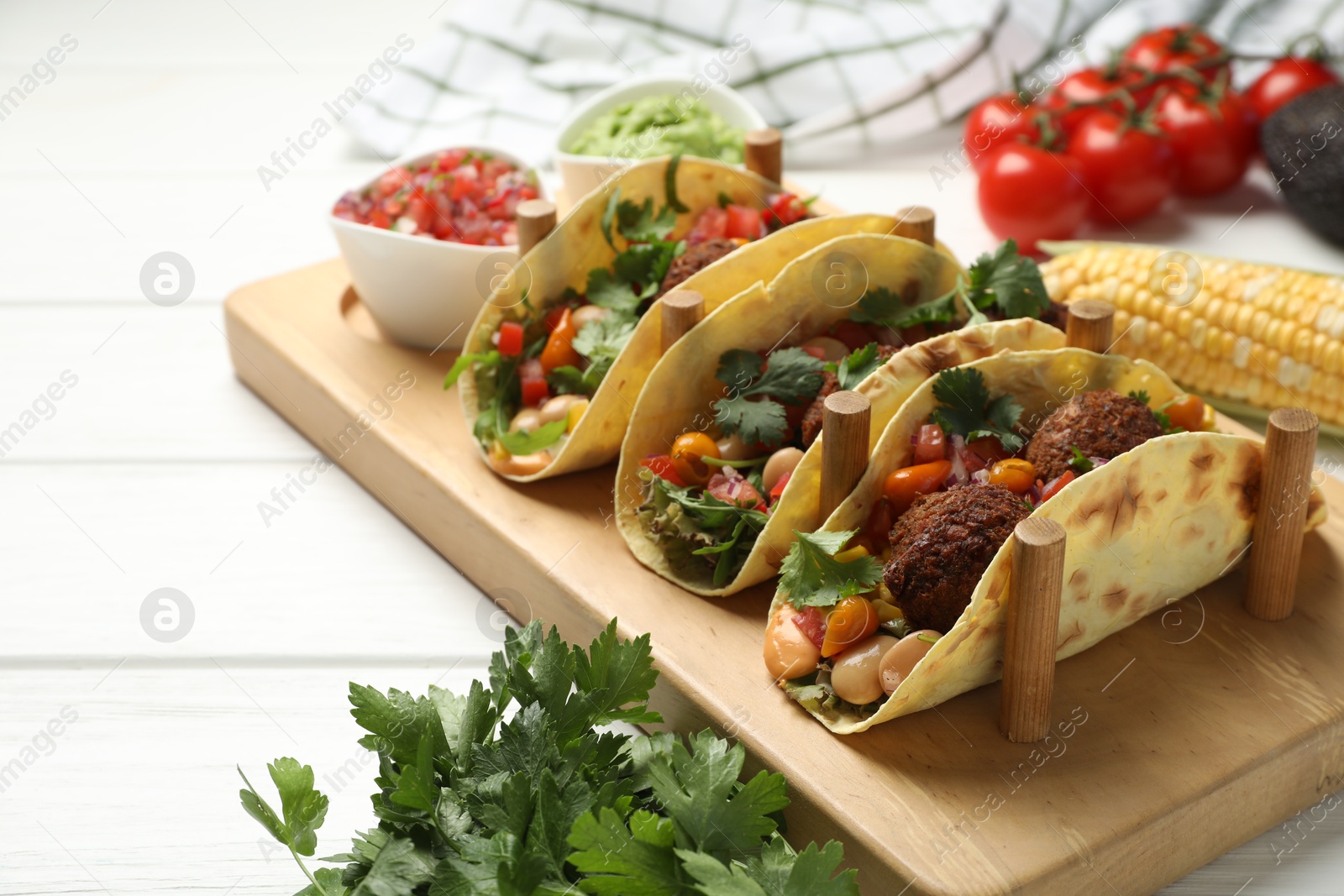 Photo of Tasty vegetarian tacos with falafel served with salsa and guacamole on white wooden table, closeup