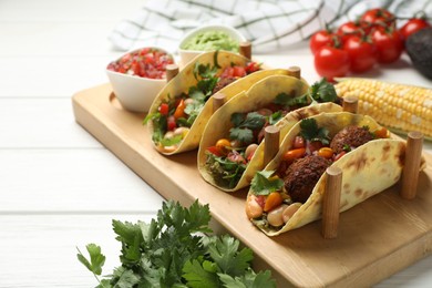 Photo of Tasty vegetarian tacos with falafel served with salsa and guacamole on white wooden table, closeup