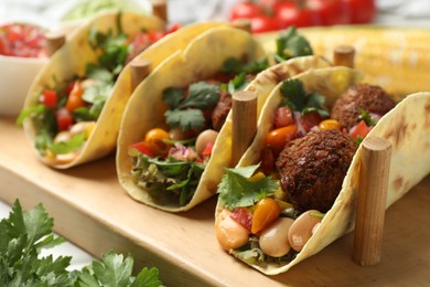 Photo of Tasty vegetarian tacos with falafel served on white wooden table, closeup