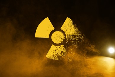 Image of Radioactive sign and yellow toxic smoke against black background