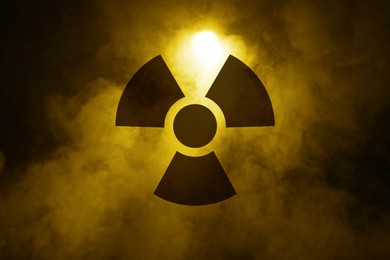 Image of Radioactive sign and yellow toxic smoke against black background