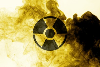 Image of Radioactive sign and yellow toxic smoke against white background