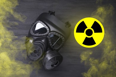Image of Radiation threat. Gas mask, radioactive sign and smoke on grey wooden background, top view