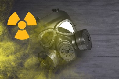Image of Radiation threat. Gas mask, radioactive sign and smoke on grey wooden background, top view