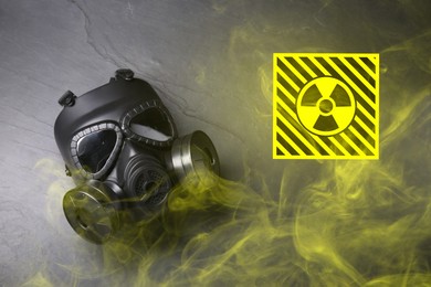 Image of Radiation threat. Gas mask, radioactive sign and smoke on grey background, top view