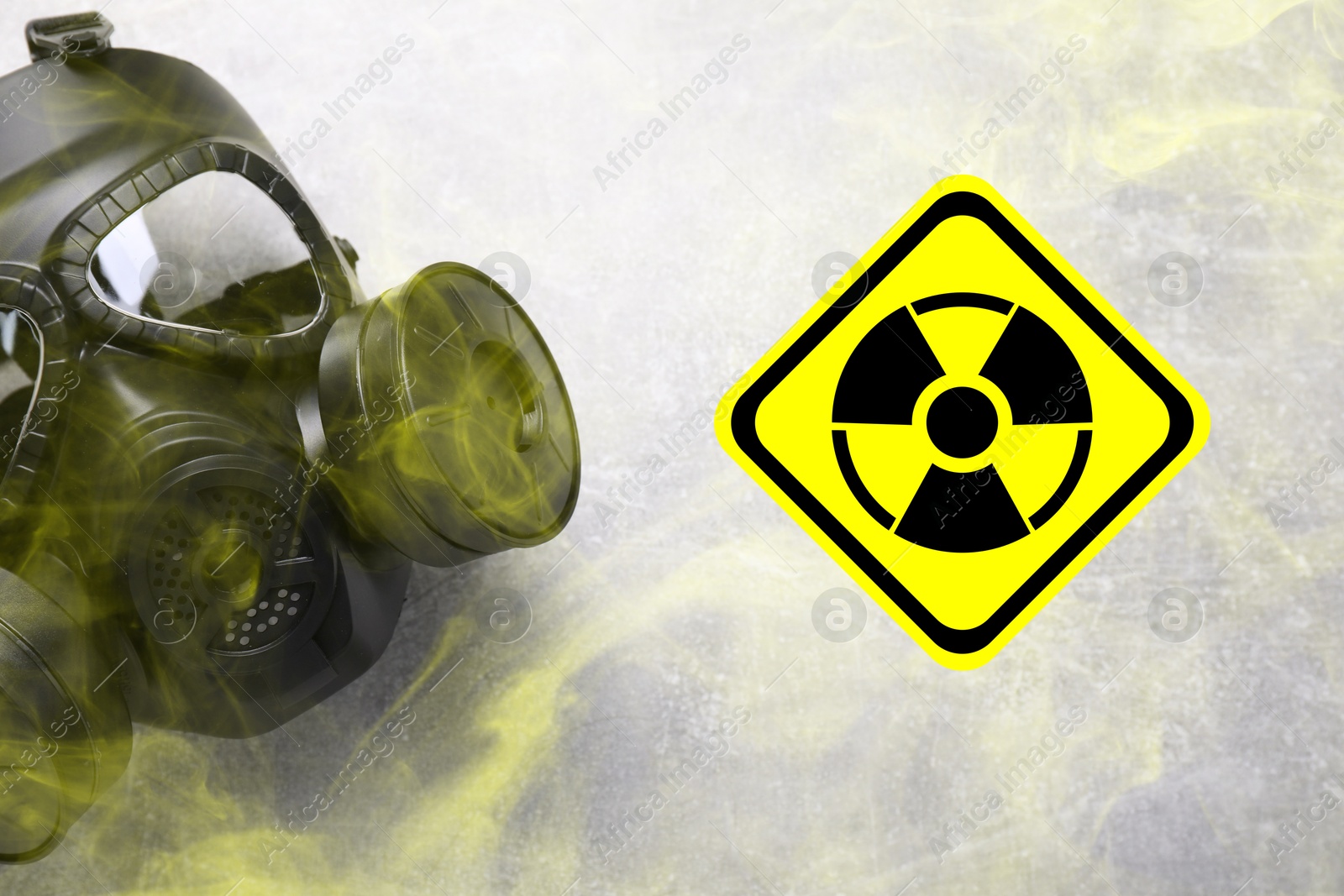 Image of Radiation threat. Gas mask, radioactive sign and smoke on grey background, top view