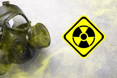 Image of Radiation threat. Gas mask, radioactive sign and smoke on grey background, top view