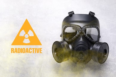 Image of Radiation threat. Gas mask, radioactive sign and smoke on grey background, top view
