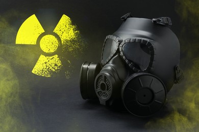 Image of Radiation threat. Gas mask, radioactive sign and smoke on grey table