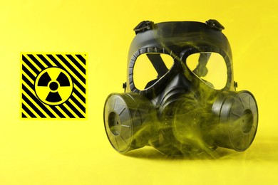 Image of Radiation threat. Gas mask, radioactive sign and smoke on yellow background