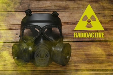 Image of Radiation threat. Gas mask, radioactive sign and smoke on wooden table, top view