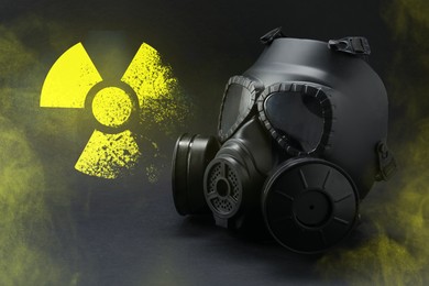Image of Radiation threat. Gas mask, radioactive sign and smoke on grey table