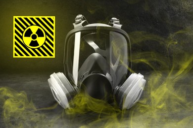 Image of Radiation threat. Gas mask, radioactive sign and smoke on grey table