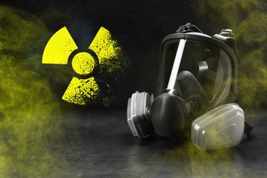 Image of Radiation threat. Gas mask, radioactive sign and smoke on grey table