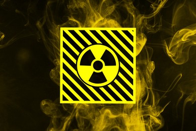 Image of Radioactive sign and yellow toxic smoke against black background