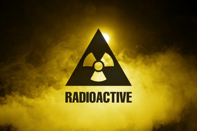Image of Radioactive sign and yellow toxic smoke against black background