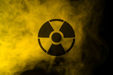 Image of Radioactive sign and yellow toxic smoke against black background