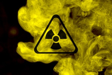 Image of Radioactive sign and yellow toxic smoke against black background