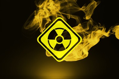Image of Radioactive sign and yellow toxic smoke against black background