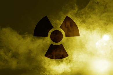 Image of Radioactive sign and yellow toxic smoke against black background