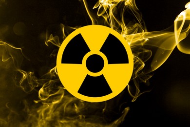 Image of Radioactive sign and yellow toxic smoke against black background