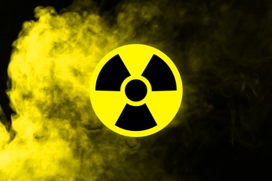 Image of Radioactive sign and yellow toxic smoke against black background