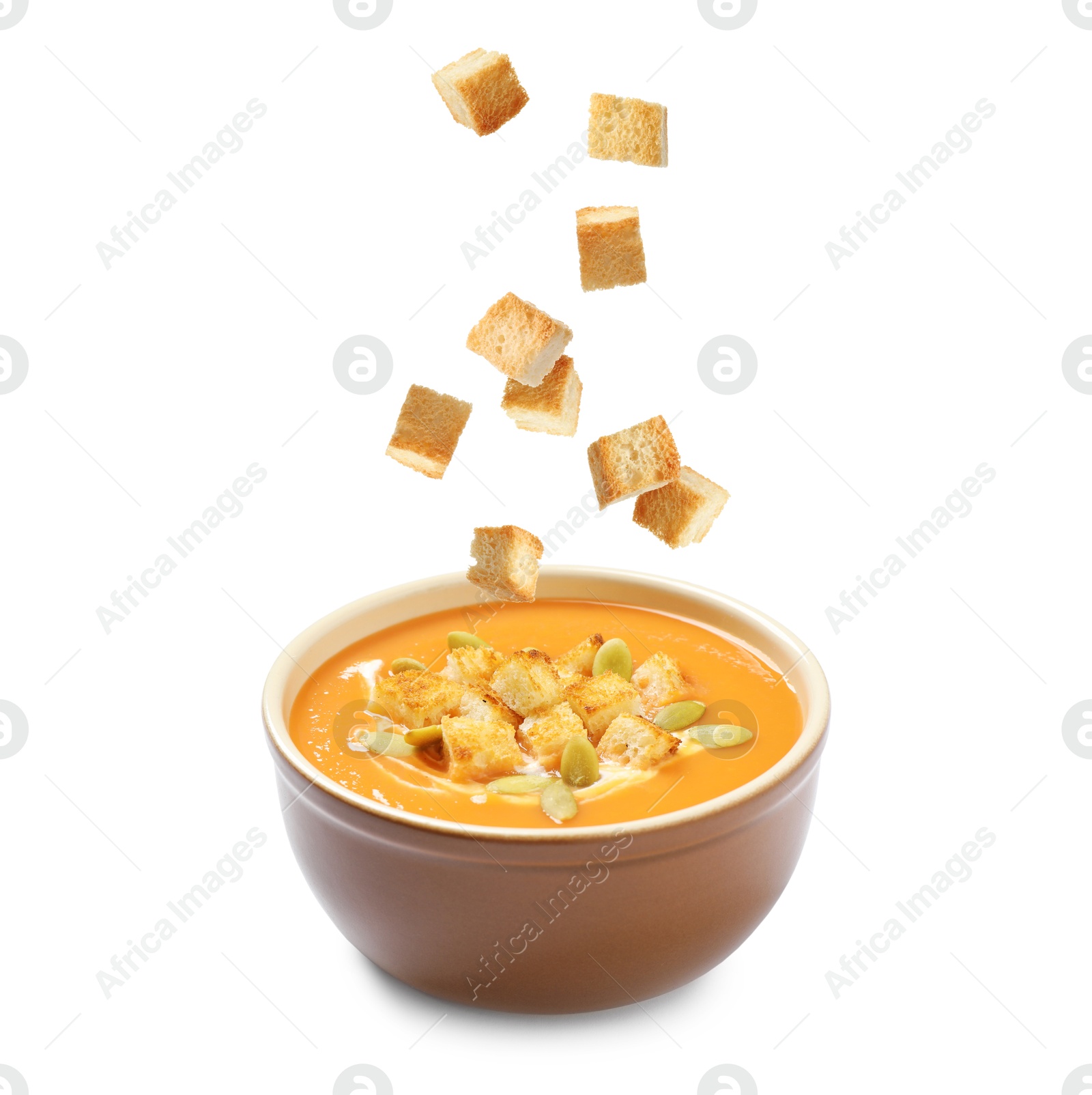 Croutons falling into bowl of creamy pumpkin soup against white background Image of Croutons falling into bowl of creamy pumpkin soup against white background