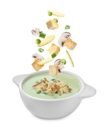 Image of Croutons, mushroom and potato slices falling into bowl of soup against white background