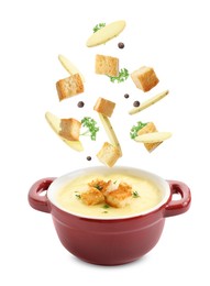 Image of Croutons and potato slices falling into bowl of soup against white background