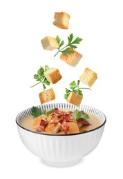 Image of Croutons and parsley falling into bowl of soup against white background
