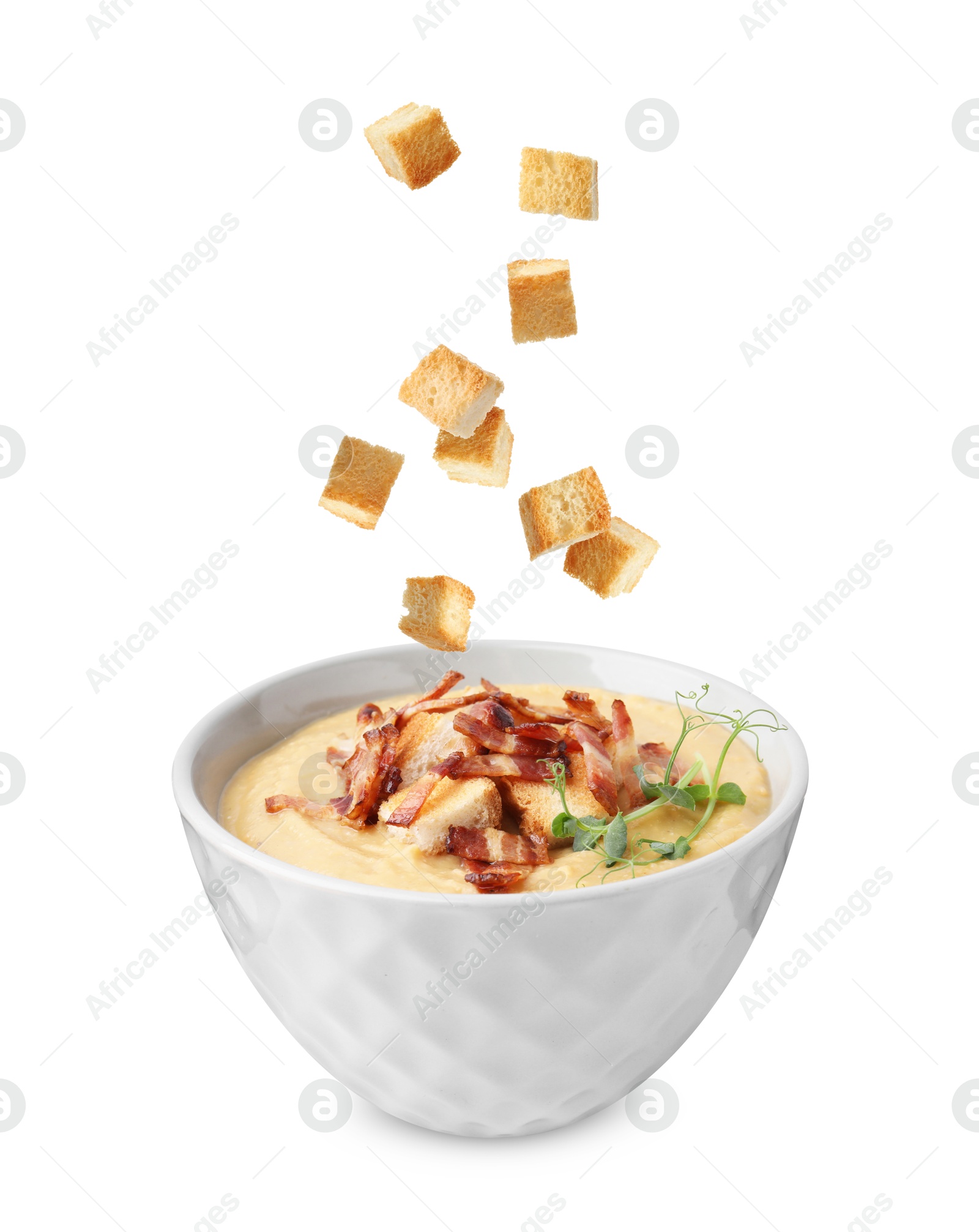 Croutons falling into bowl of soup against white background Image of Croutons falling into bowl of soup against white background