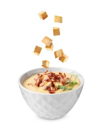 Image of Croutons falling into bowl of soup against white background