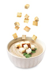 Image of Croutons falling into bowl of soup against white background