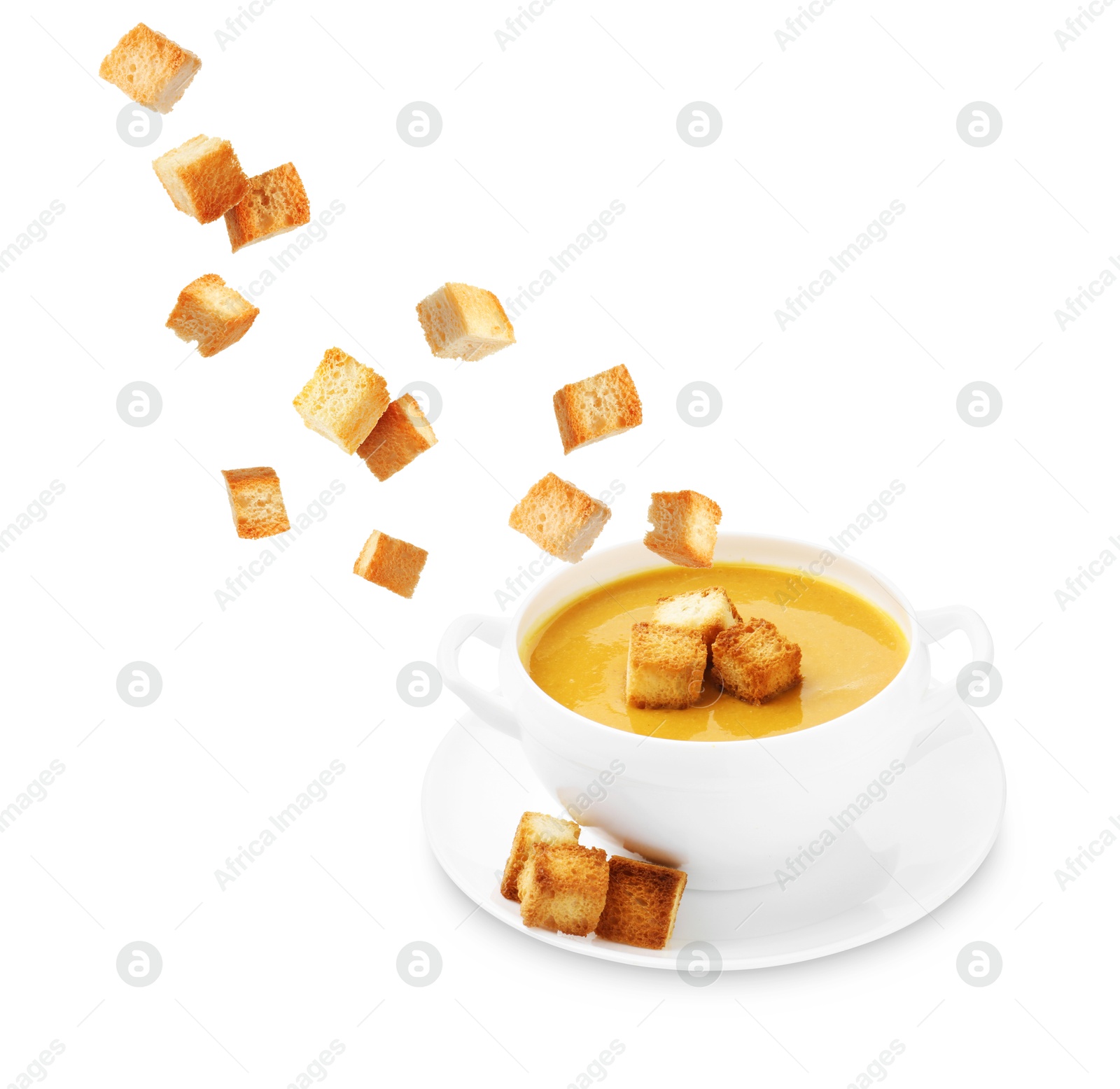 Image of Croutons falling into bowl of soup against white background
