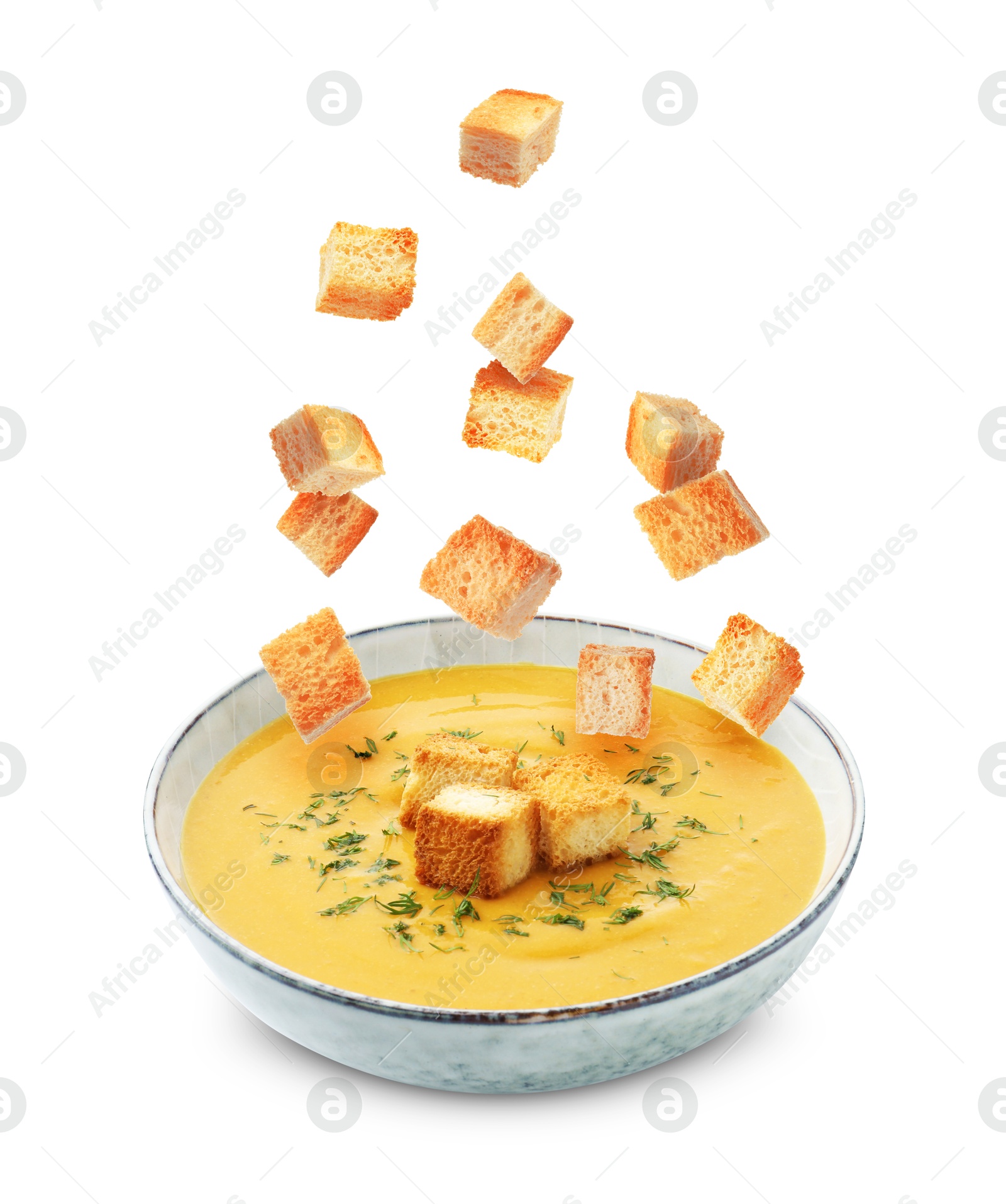 Croutons falling into bowl of soup against white background Image of Croutons falling into bowl of soup against white background