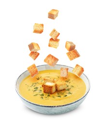 Image of Croutons falling into bowl of soup against white background