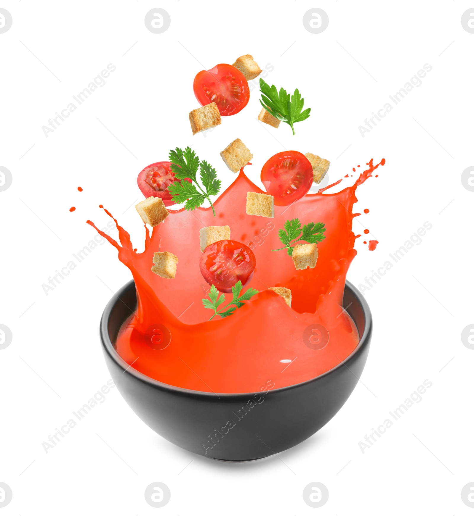 Image of Croutons and tomatoes falling into bowl of soup against white background