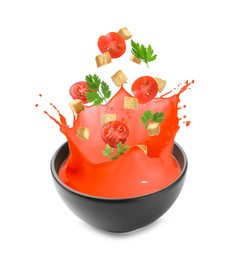 Image of Croutons and tomatoes falling into bowl of soup against white background