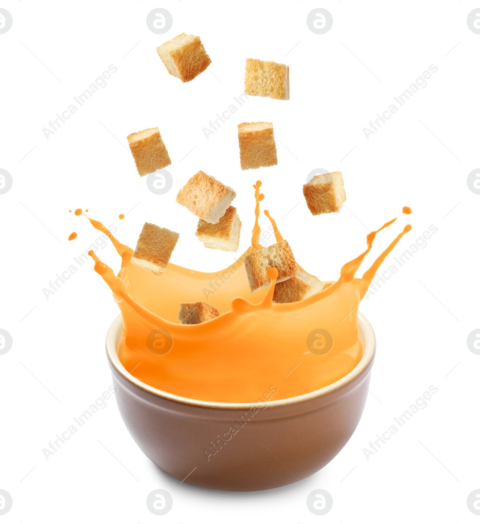 Image of Croutons falling into bowl of soup against white background