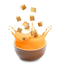Image of Croutons falling into bowl of soup against white background