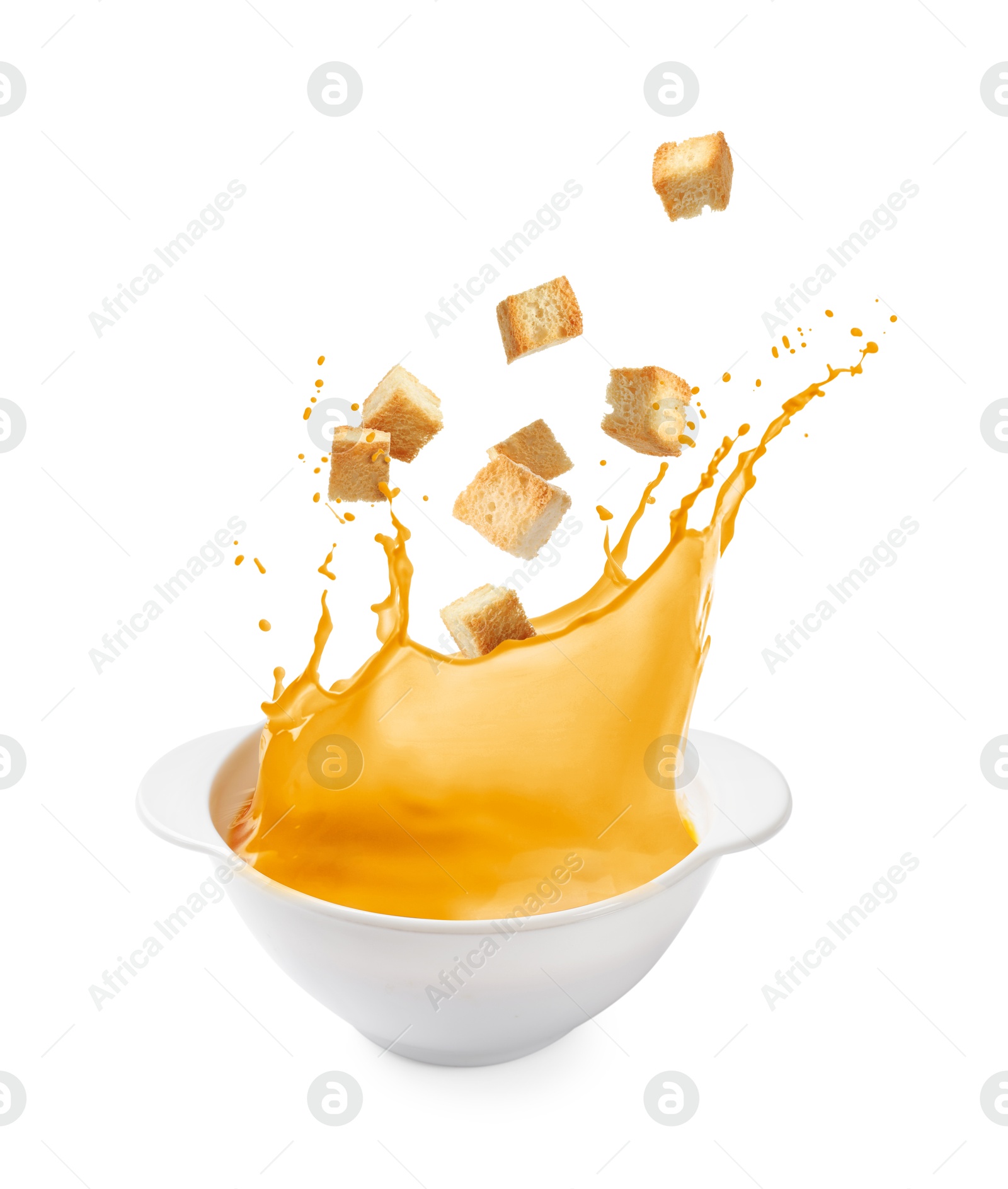 Croutons falling into bowl of soup against white background Image of Croutons falling into bowl of soup against white background